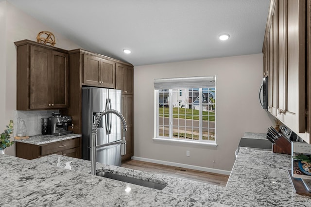 5928 Th St W, Lakeville, MN 55044 - kitchen with stainless steel appliances, baseboards, light stone counters, light wood-style floors, and a sink