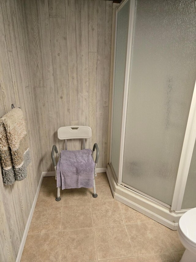 218 Lake Ave E, Fulda, MN 56131 - full bathroom featuring a shower stall, toilet, tile patterned floors, wooden walls, and baseboards