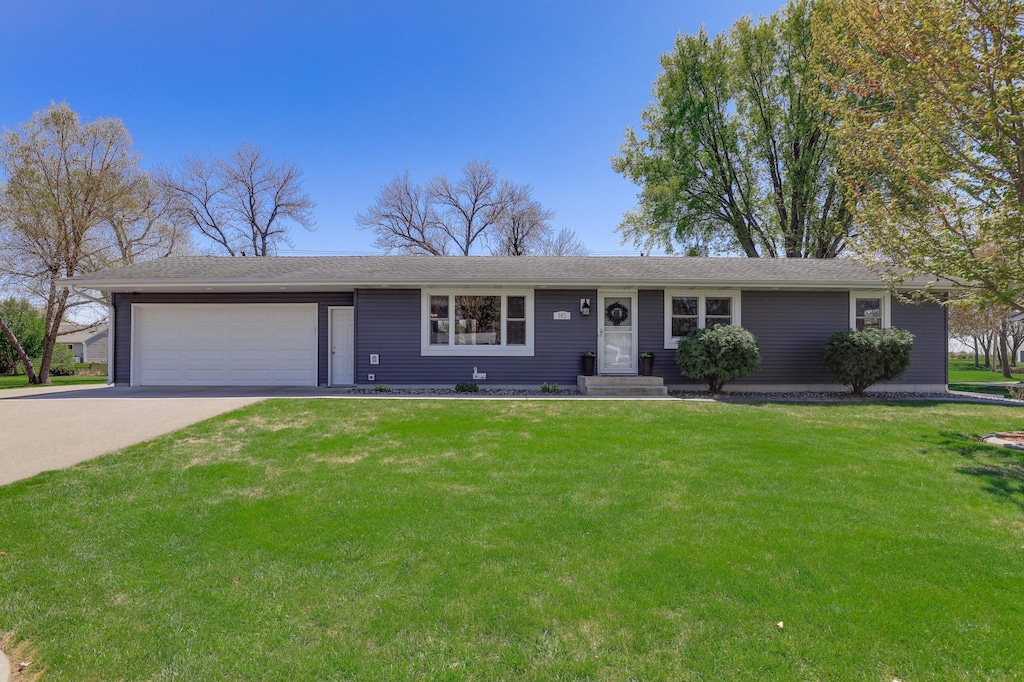 ranch-style home with concrete driveway, a front lawn, and an attached garage