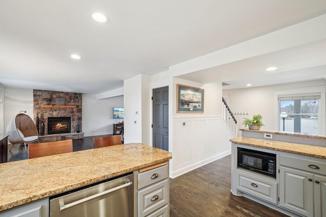 kitchen featuring stainless steel dishwasher, a wainscoted wall, dark wood finished floors, gray cabinetry, and black microwave