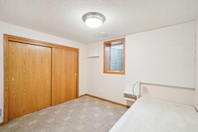 unfurnished bedroom with a textured ceiling, visible vents, baseboards, light colored carpet, and a closet