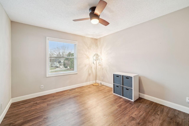 spare room featuring baseboards, wood finished floors, a textured ceiling, and ceiling fan