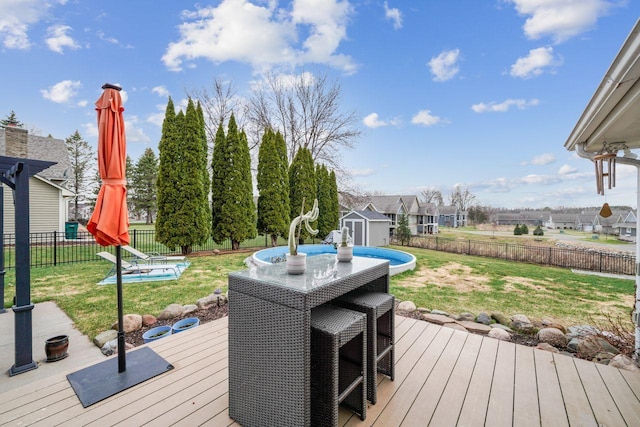 wooden deck featuring a storage unit, a fenced backyard, an outdoor structure, a yard, and outdoor dining area