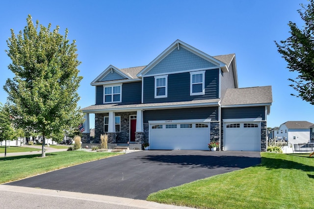 craftsman inspired home with a front lawn, driveway, stone siding, and an attached garage
