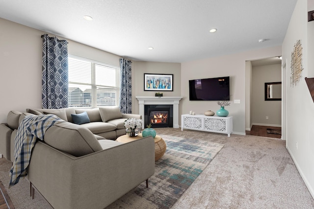 carpeted living area with recessed lighting, a glass covered fireplace, and baseboards
