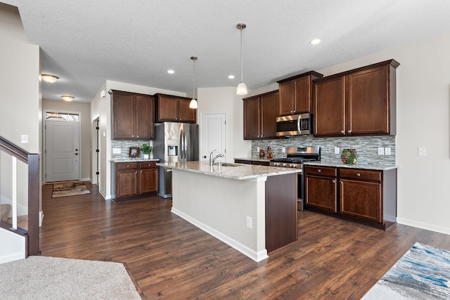 kitchen with dark brown cabinets, decorative backsplash, stainless steel appliances, light stone countertops, and dark wood-style floors