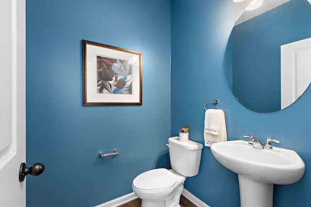 bathroom featuring wood finished floors, baseboards, a sink, and toilet