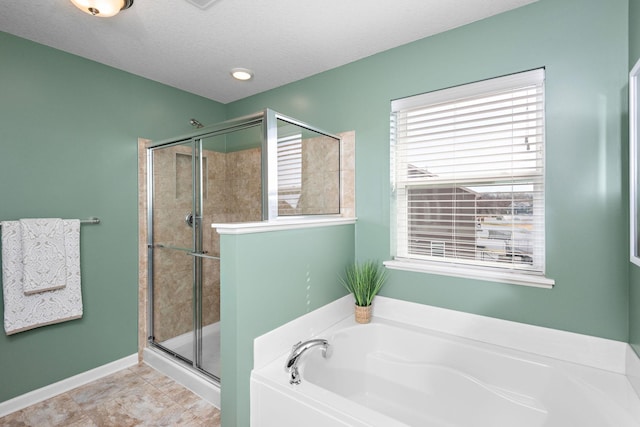 bathroom with a textured ceiling, baseboards, a garden tub, and a stall shower