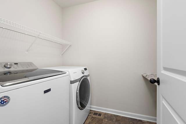 washroom featuring washer and clothes dryer, laundry area, stone finish flooring, baseboards, and visible vents