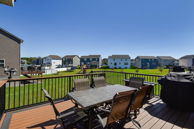 deck featuring a residential view, a lawn, and outdoor dining area