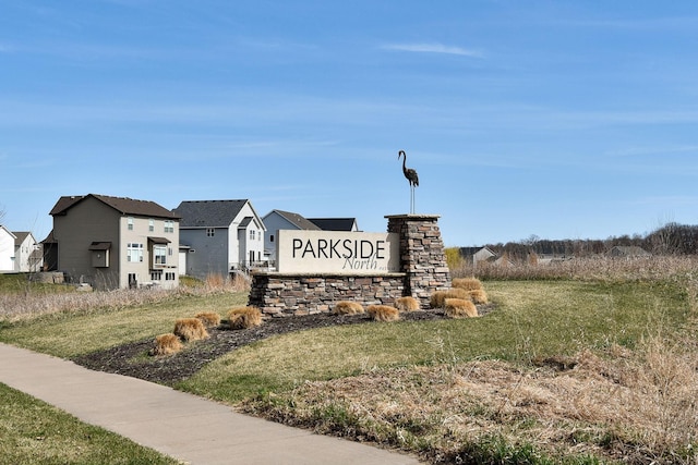 community / neighborhood sign featuring a residential view and a lawn