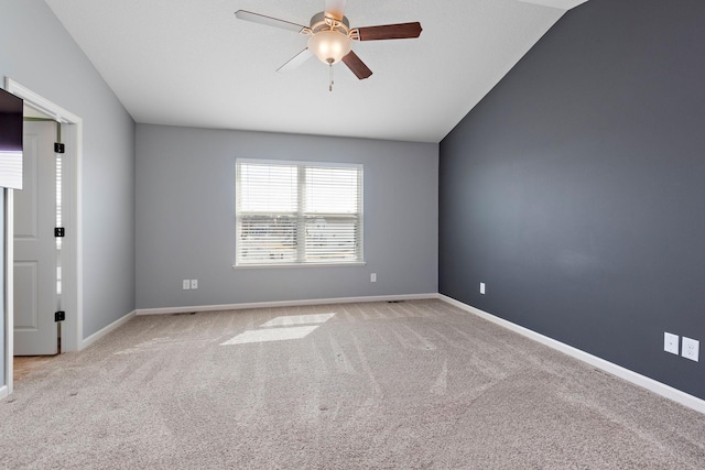 carpeted spare room with ceiling fan, vaulted ceiling, and baseboards