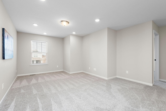 carpeted spare room featuring baseboards, visible vents, and recessed lighting