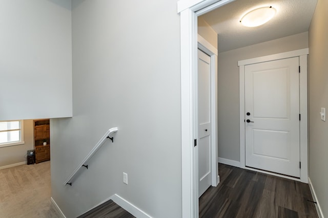 corridor featuring wood finished floors, baseboards, and an upstairs landing