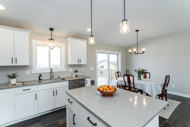 kitchen with lofted ceiling, dark wood-style floors, dishwasher, a sink, and a notable chandelier