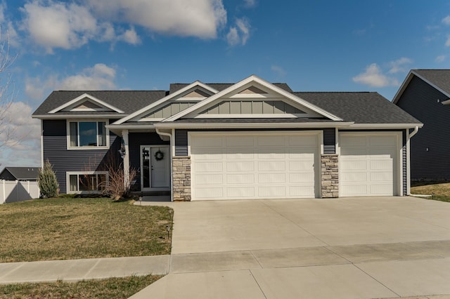 craftsman-style home featuring an attached garage, driveway, stone siding, and a front lawn