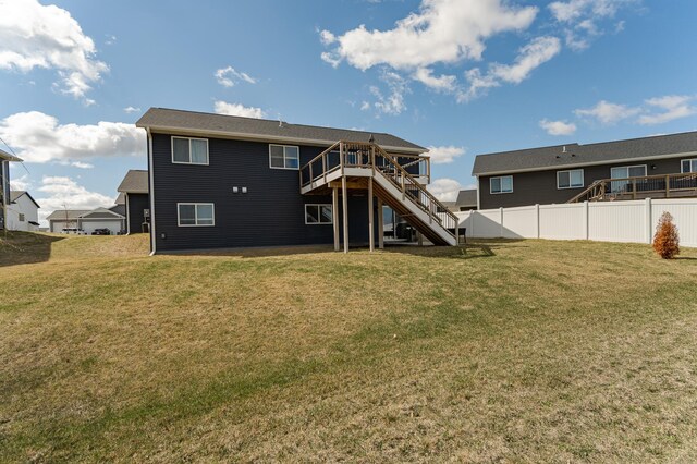 back of property with a wooden deck, a lawn, stairs, and fence