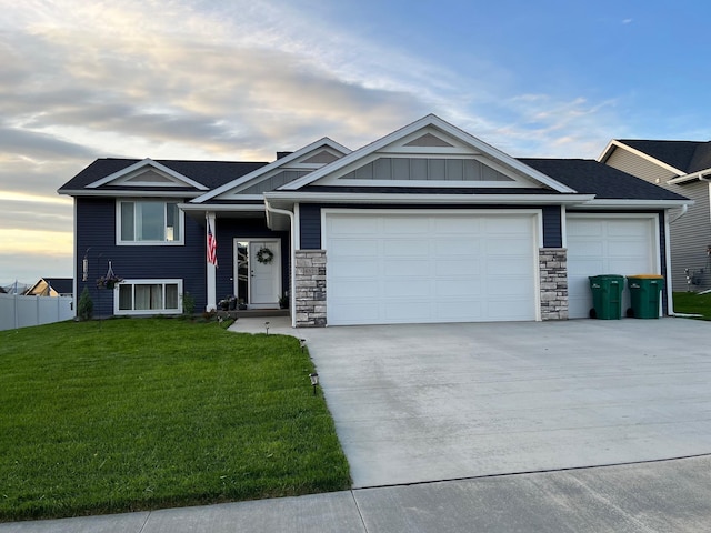 view of front of property with an attached garage, stone siding, a front yard, and concrete driveway