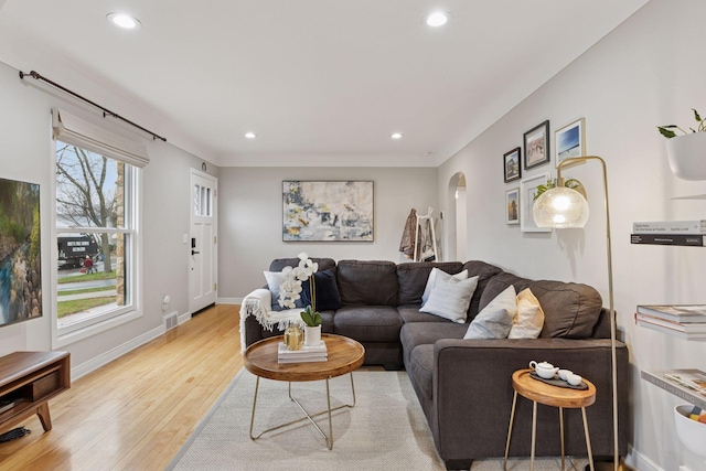living area with visible vents, arched walkways, baseboards, light wood-style floors, and recessed lighting