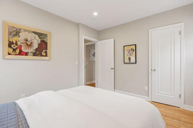 bedroom with baseboards, recessed lighting, and light wood-style flooring