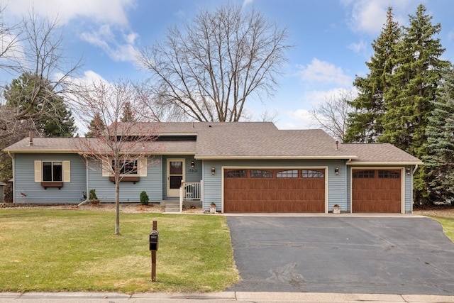 view of front of house with a shingled roof, aphalt driveway, a front yard, and a garage