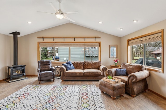living area with vaulted ceiling, a wealth of natural light, light wood-style floors, and a ceiling fan