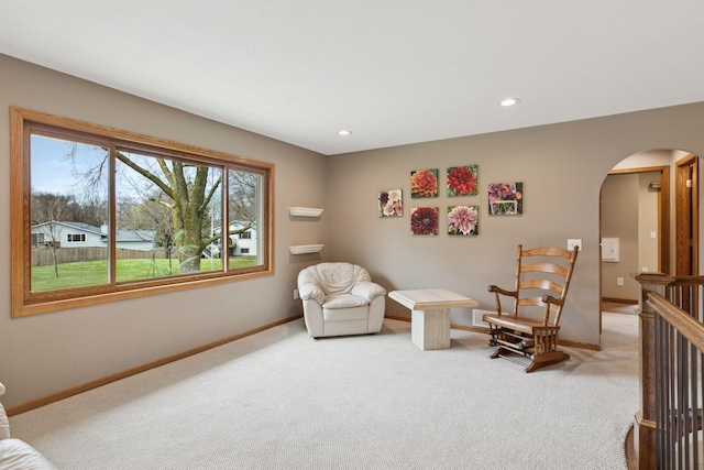 sitting room featuring baseboards, arched walkways, recessed lighting, and light colored carpet
