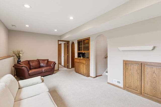 living area featuring arched walkways, light carpet, visible vents, and recessed lighting