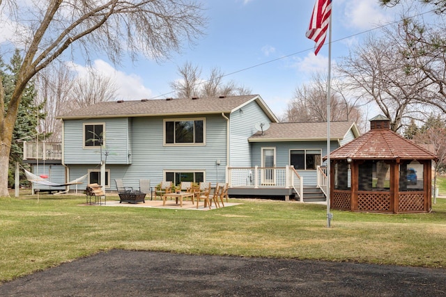 back of house featuring a lawn, an outdoor fire pit, a gazebo, and a deck