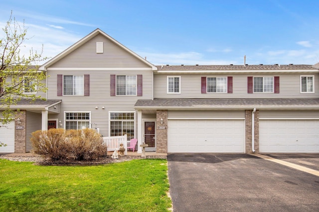 view of front of house featuring brick siding, a front lawn, and aphalt driveway