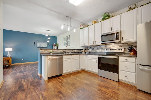kitchen featuring appliances with stainless steel finishes, decorative backsplash, a peninsula, and white cabinets