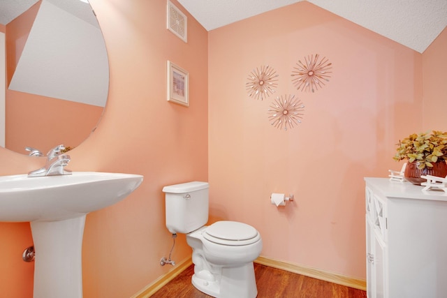 half bath featuring baseboards, toilet, wood finished floors, and visible vents