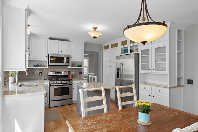 kitchen featuring open shelves, white cabinets, a sink, and appliances with stainless steel finishes