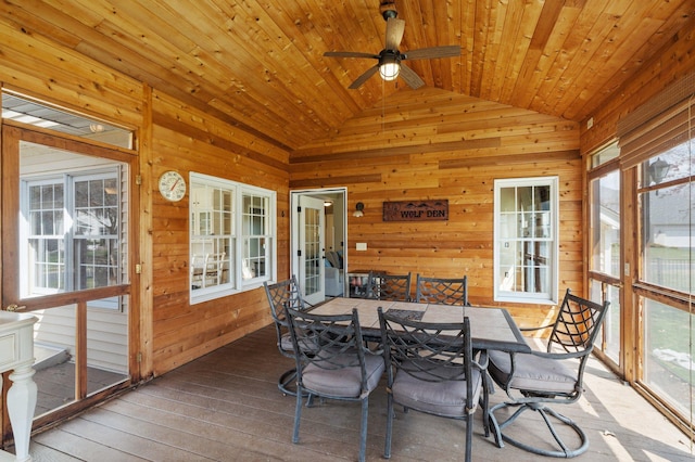 sunroom / solarium featuring wood walls, a healthy amount of sunlight, and vaulted ceiling