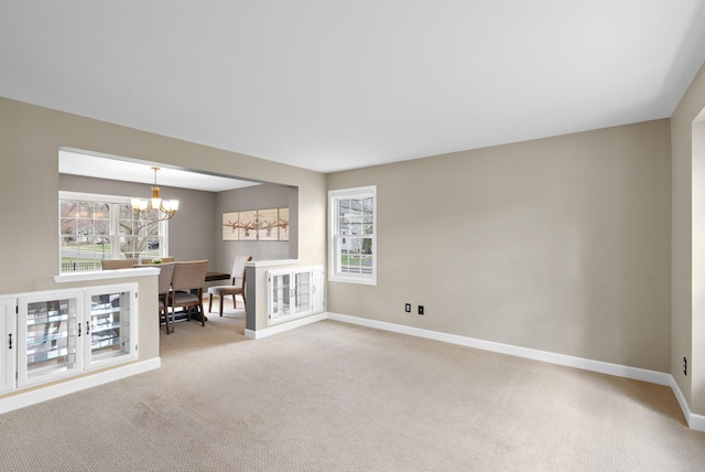 unfurnished living room with baseboards, carpet floors, and a chandelier