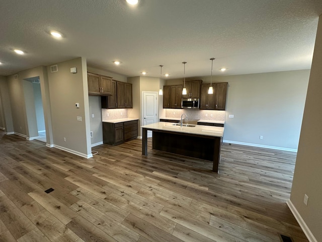 2063 Oakpointe Dr, Waconia, MN 55387 - kitchen with stainless steel microwave, dark wood-type flooring, light countertops, recessed lighting, and backsplash
