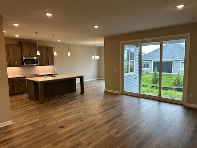 2063 Oakpointe Dr, Waconia, MN 55387 - kitchen featuring stainless steel microwave, dark wood-style flooring, decorative backsplash, light countertops, and recessed lighting