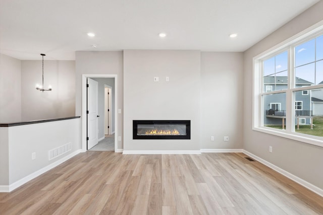 1274 Orchard Ct, Waconia, MN 55387 - unfurnished living room with light wood-type flooring, a chandelier, a glass covered fireplace, and recessed lighting
