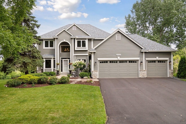 view of front of home with a front yard, aphalt driveway, a shingled roof, and a garage
