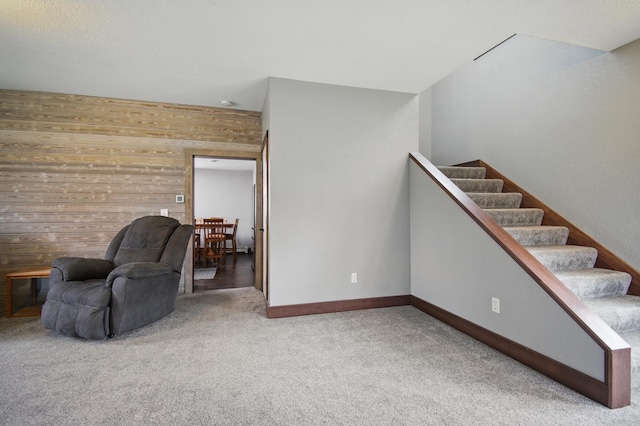 235 3rd St NE, Blooming Prairie, MN 55917 - sitting room with baseboards, carpet, wood walls, and stairs