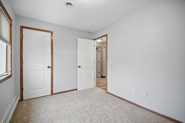 235 3rd St NE, Blooming Prairie, MN 55917 - unfurnished bedroom featuring a baseboard heating unit, visible vents, carpet flooring, and baseboards