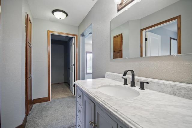 235 3rd St NE, Blooming Prairie, MN 55917 - bathroom with a textured wall, baseboards, and vanity