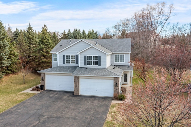 traditional-style home featuring brick siding, an attached garage, aphalt driveway, and roof with shingles