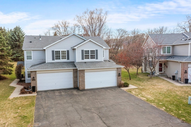 view of front of home with aphalt driveway, a front lawn, roof with shingles, an attached garage, and brick siding
