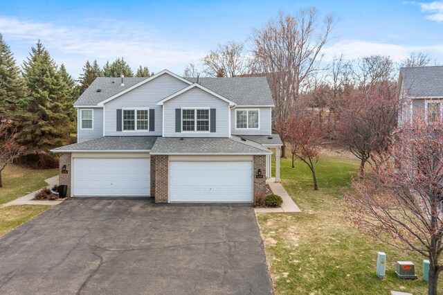 view of front of house with driveway, a garage, brick siding, a shingled roof, and a front yard