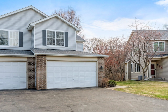 view of home's exterior featuring a lawn, aphalt driveway, a shingled roof, an attached garage, and brick siding