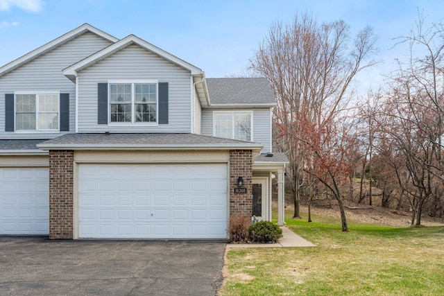view of front of house with a front lawn, aphalt driveway, a shingled roof, a garage, and brick siding
