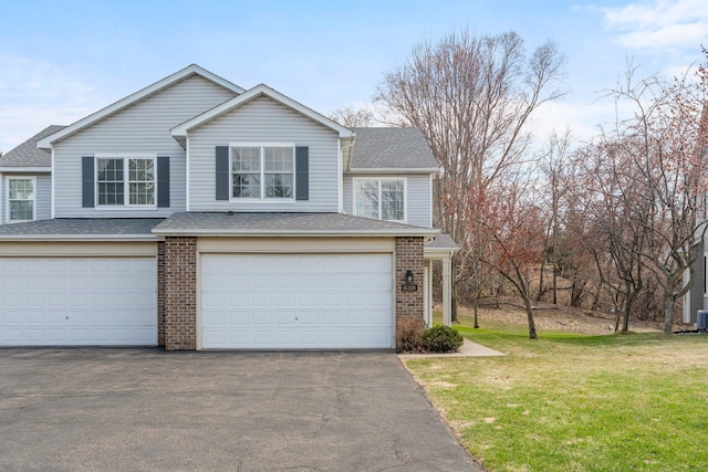 view of front of property featuring driveway, a front yard, a shingled roof, and a garage