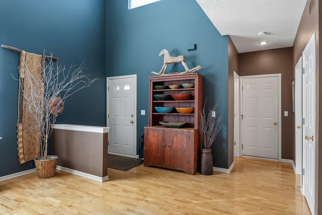 entryway with wood finished floors, a textured ceiling, baseboards, and visible vents
