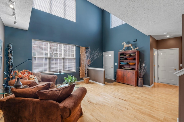 living room featuring track lighting, baseboards, wood finished floors, and a textured ceiling